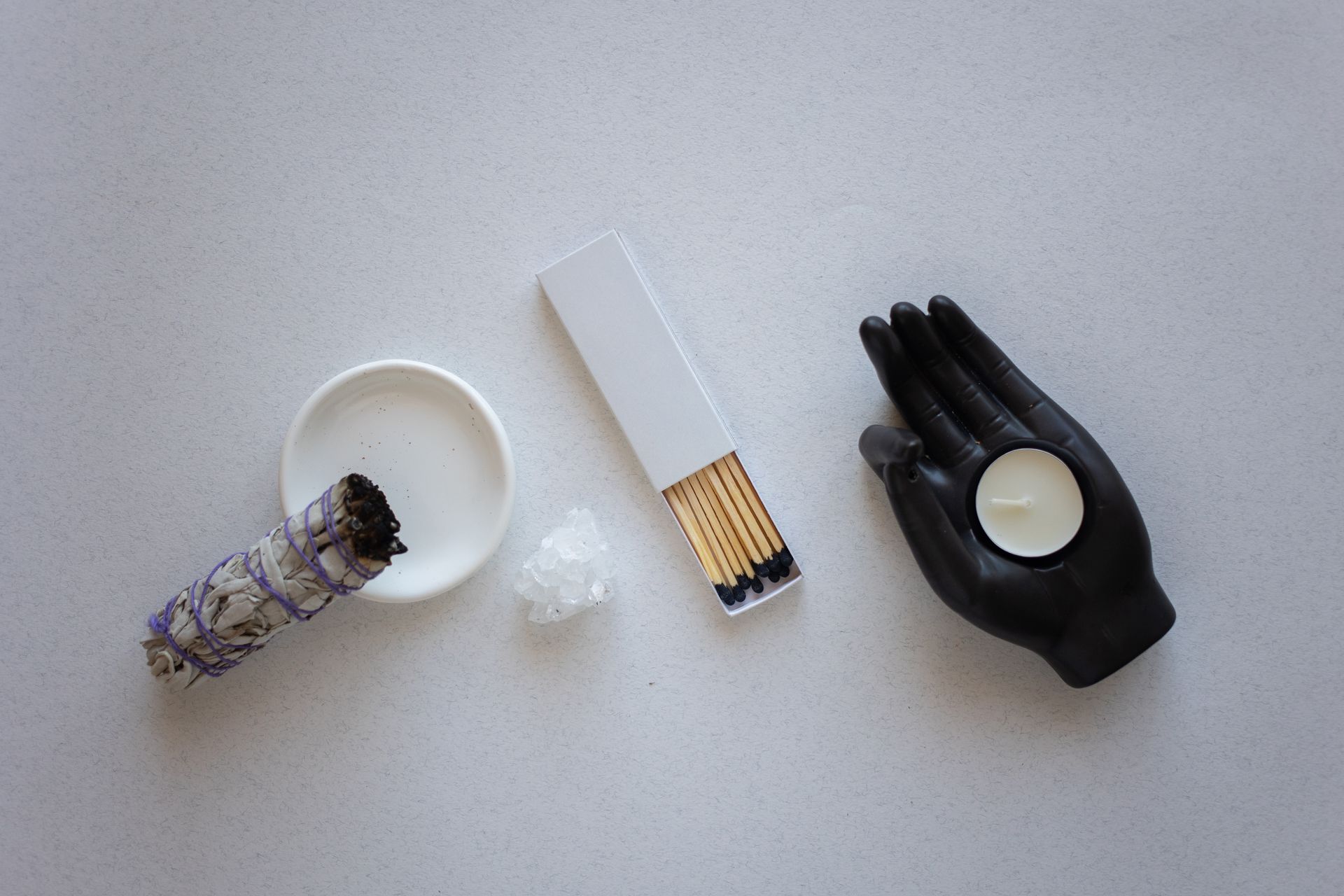 A top view of spiritual decor with a candle, sage bundle, and matches on a minimalist background.