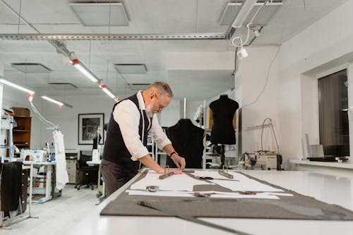 A Couturier Marking a Gray Fabric on a Table