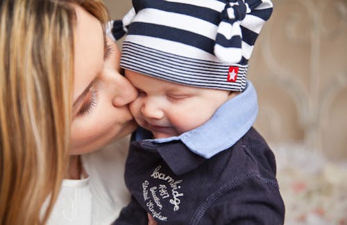 Woman in White Shirt Kissing Baby With Black and White Stripe Knit Cap