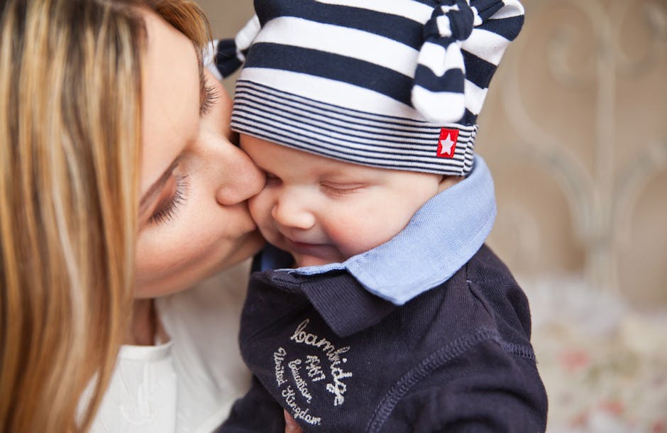 Woman in White Shirt Kissing Baby With Black and White Stripe Knit Cap