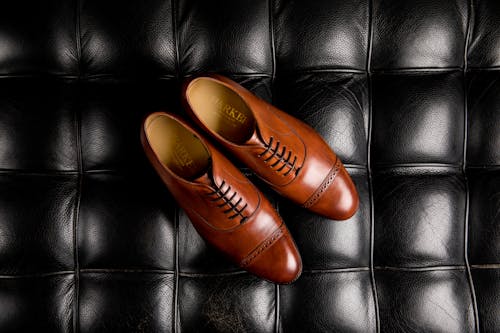 A Pair of Brown Oxford Shoes on Black Surface