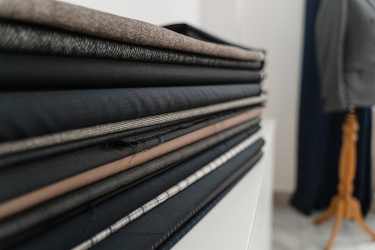 A Stack Of Assorted Folded Fabrics On A Shelf