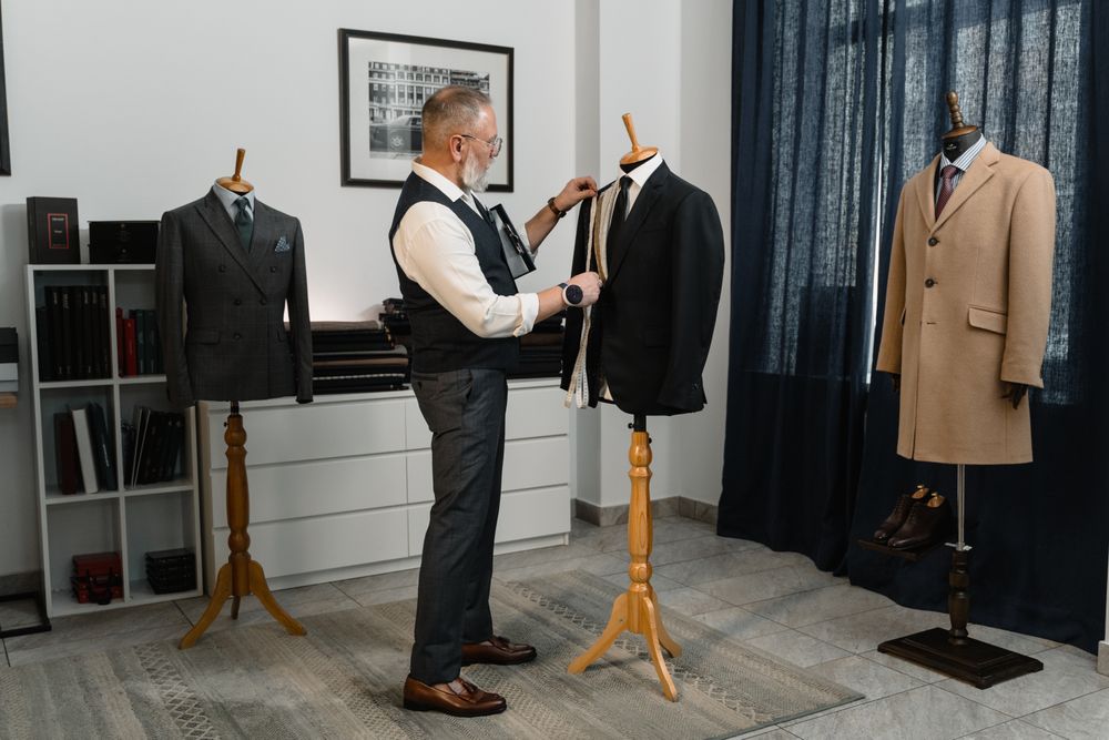 Tailor adjusting a formal black suit jacket in a professional studio