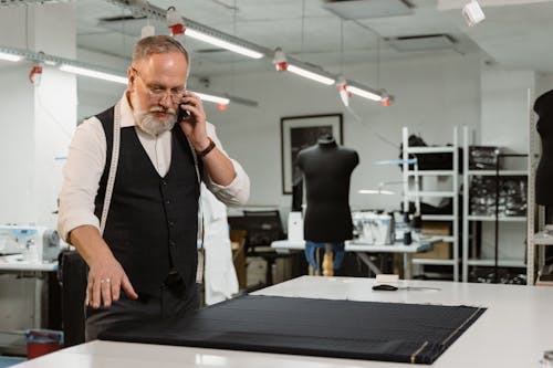 Man in Black Vest and White Long Sleeve Shirt Talking on the Phone