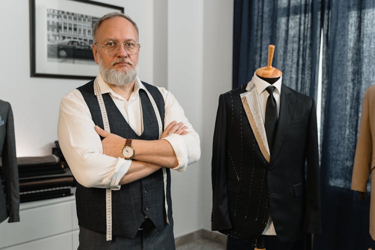 Man In Black Vest Standing Beside Mannequin Wearing Black Suit 