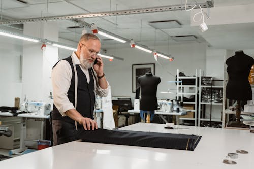 Man in White Long Sleeve Shirt and Black Vest Holding Black Fabric