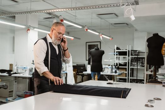 Man in White Long Sleeve Shirt and Black Vest Holding Black Fabric