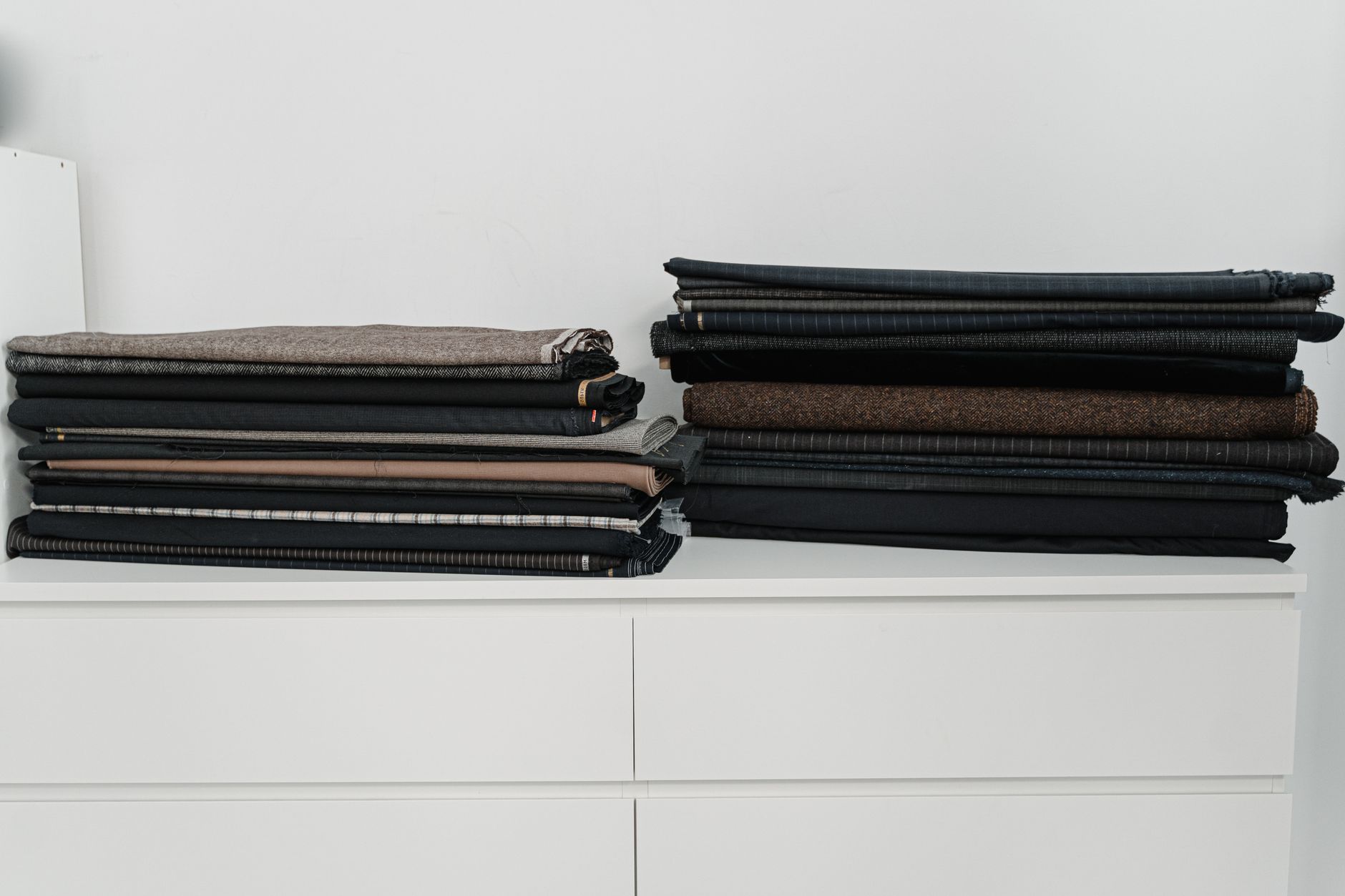 Three wool coat storage methods compared: a plastic garment bag, a lidded storage bin, and a breathable cotton bag with cedar blocks