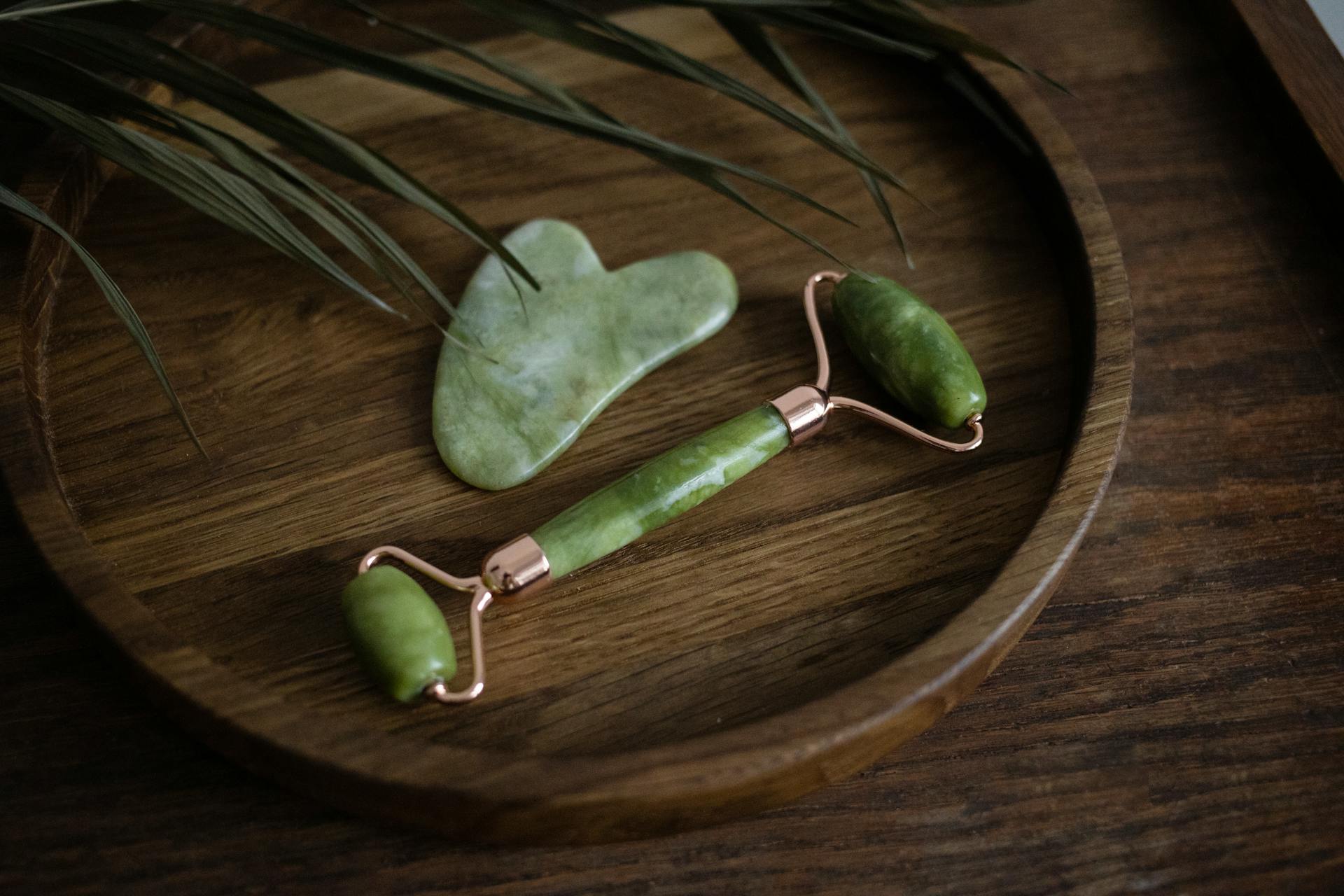 Close-up of jade roller and gua sha set elegantly displayed on a wooden tray with a natural aesthetic.