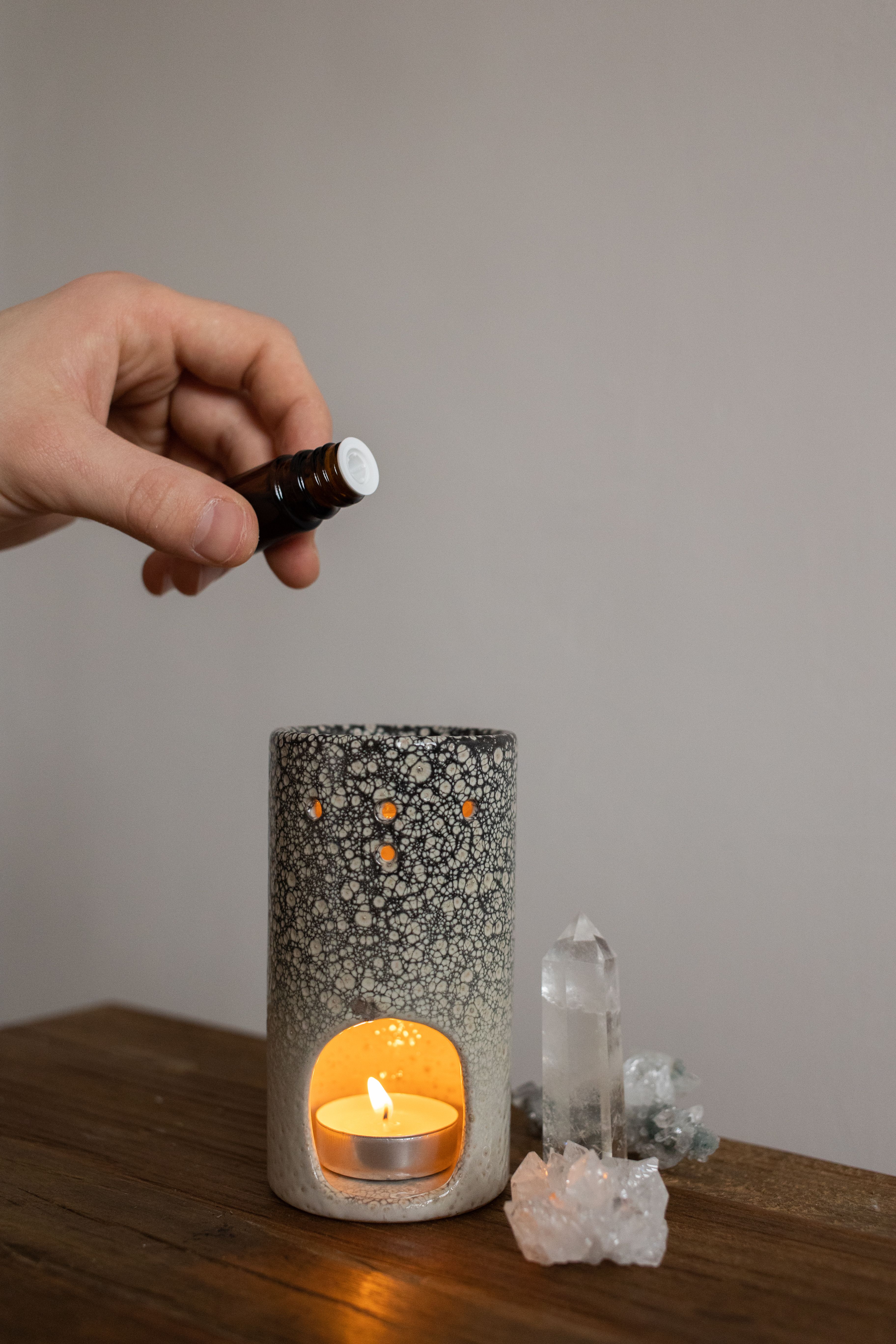 A cozy aromatherapy scene with candle holder, essential oil, and crystals creating a calm atmosphere.