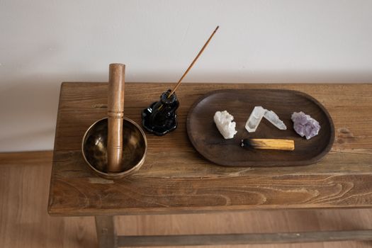 A calming zen setup featuring a singing bowl, incense, crystals, and wood elements.