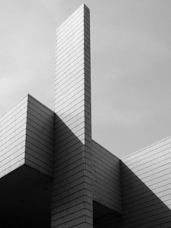 Free From below black and white of contemporary geometric construction exterior with tall walls under light cloudy sky in sunny day Stock Photo