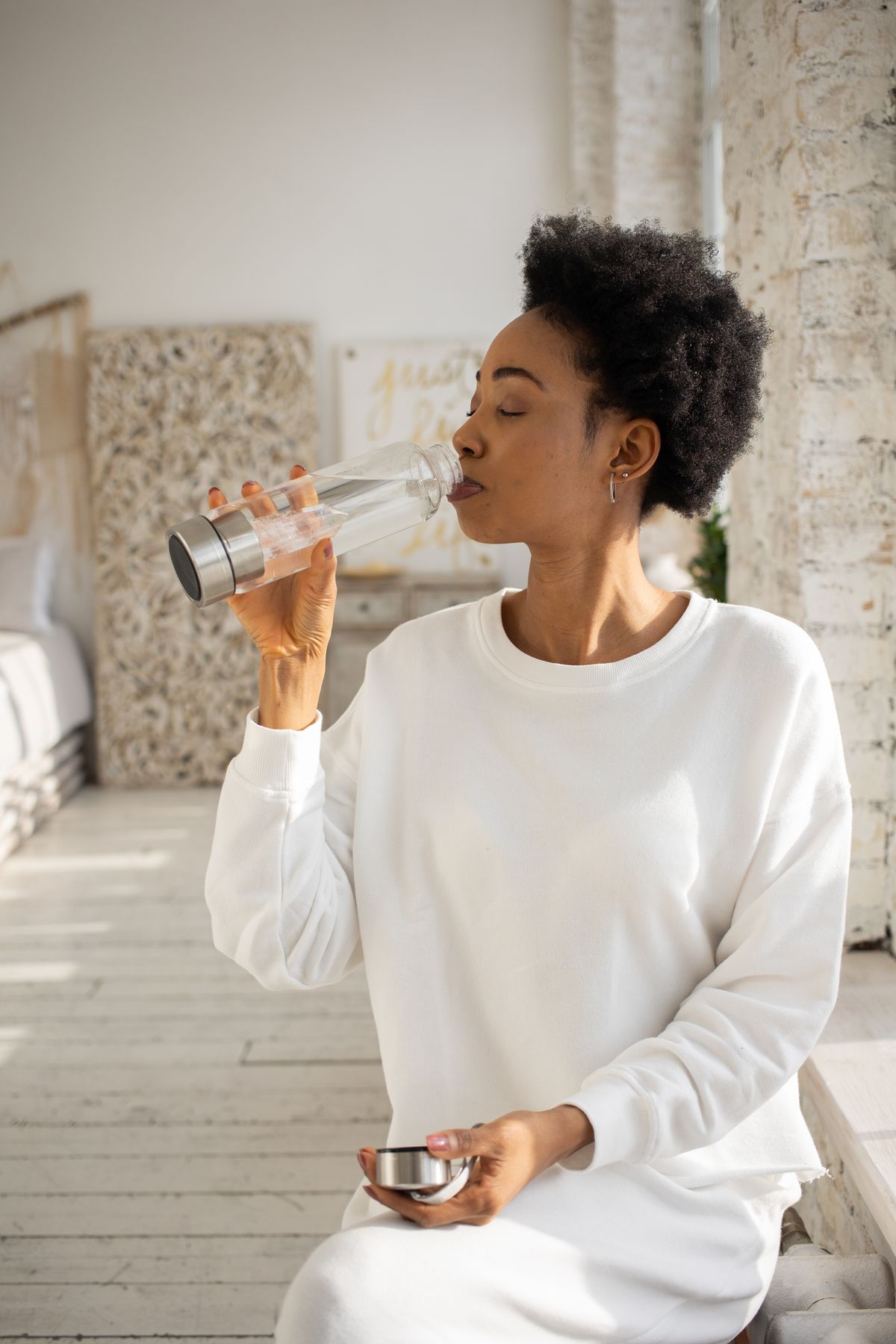 Woman drinking water in the morning as part of a wellness and preconception routine