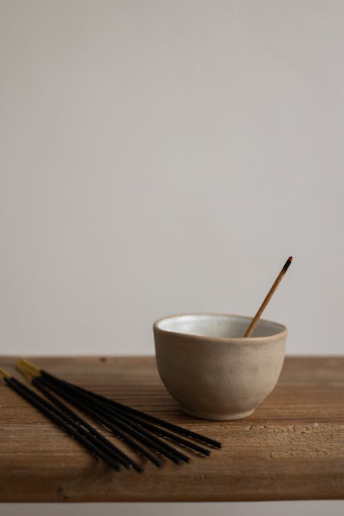 Incense Sticks and a Bowl on a Wooden Surface 