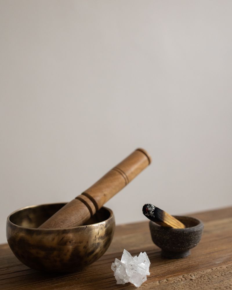 木桌上的頌缽與缽棒、白水晶簇與聖木,靜謐淨化儀式