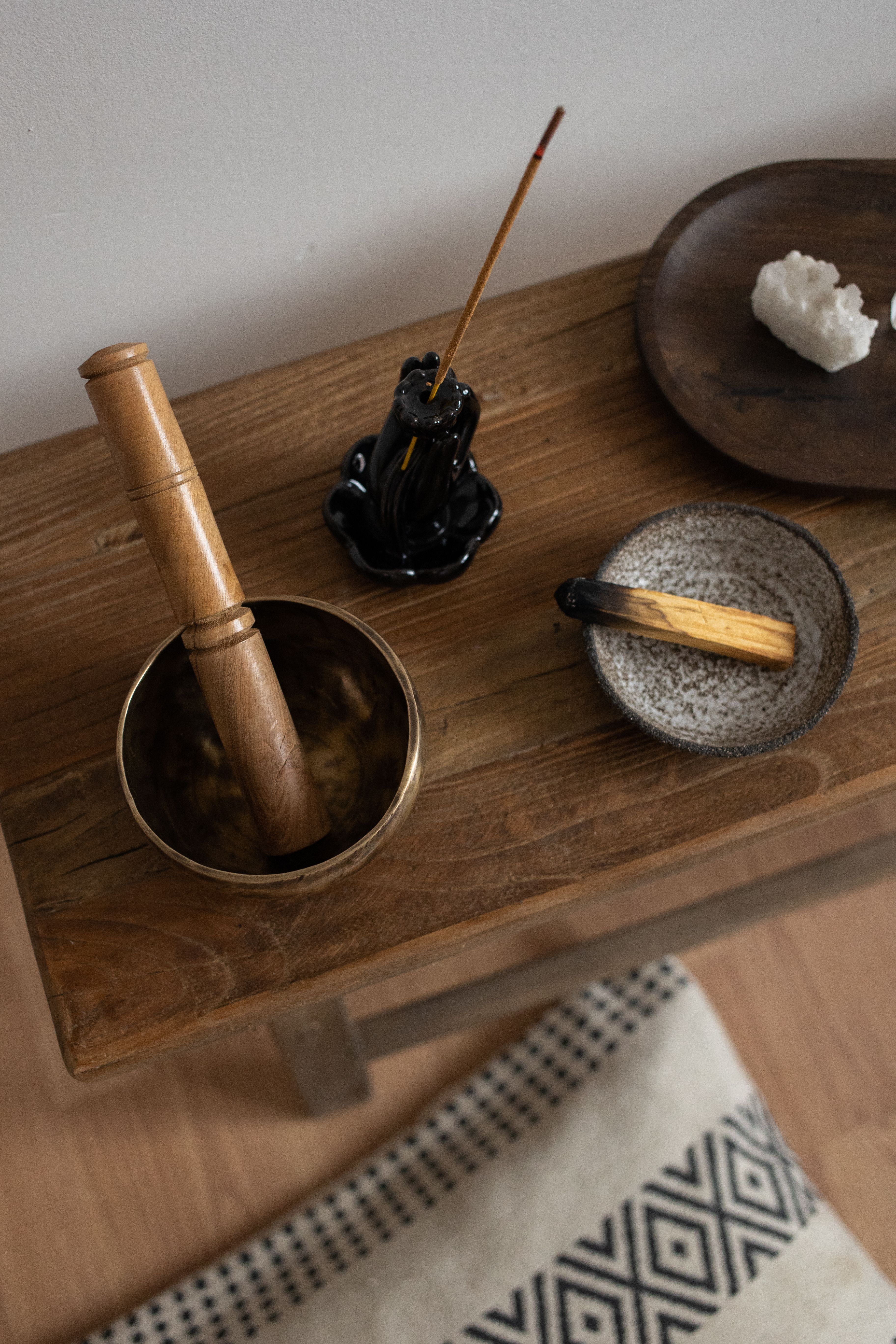A serene meditation setup featuring palo santo, incense, and a wooden table with healing crystals.
