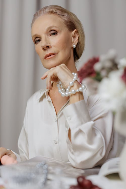 Woman in White long Sleeves Holding a Pearl Necklace