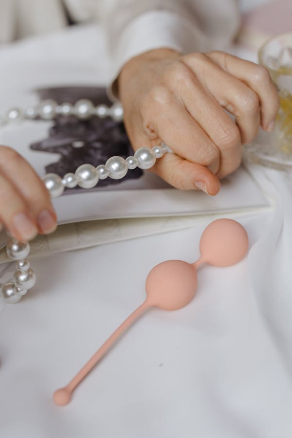 Person Holding Pearl Necklace Near Ben Wa Balls