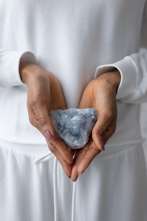 Free Adult hands in white clothes holding a raw mineral crystal, close-up view. Stock Photo