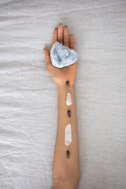 Free A serene arrangement of crystals on an arm over a soft linen backdrop, emphasizing holistic healing. Stock Photo