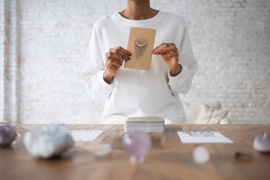 A person meditating with eyes closed, a few tarot cards placed in front, serene atmosphere