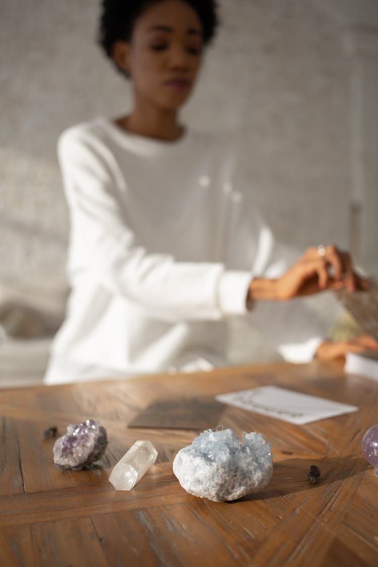 Woman Sitting By A Table With Crystals On It