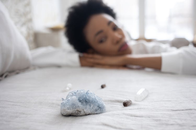 Woman Looking At Crystals On Her Bed