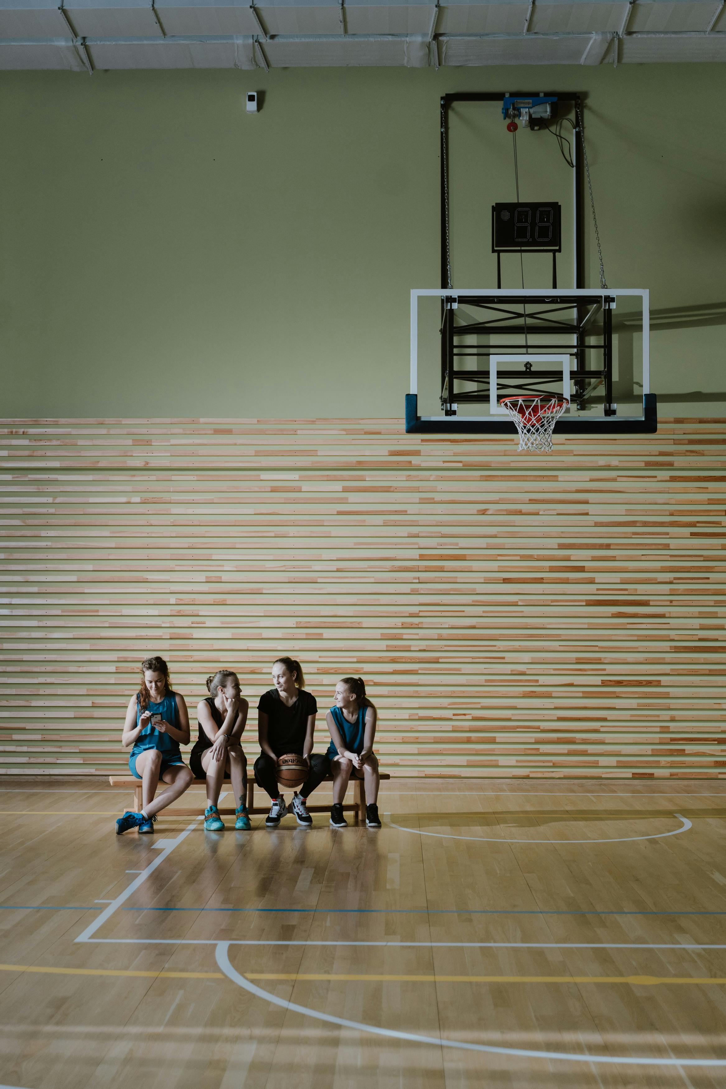 women sitting on a bench in a basketball court