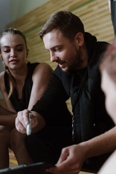 Coach discussing strategy with basketball players during a team huddle indoors.