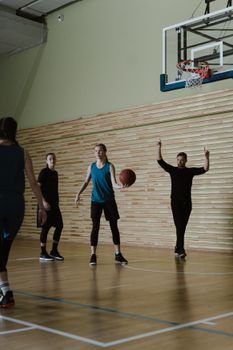 Group of young basketball players practicing on an indoor court with a coach.