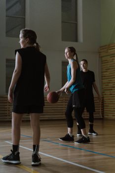 Three women playing basketball indoors, showcasing teamwork and athleticism.