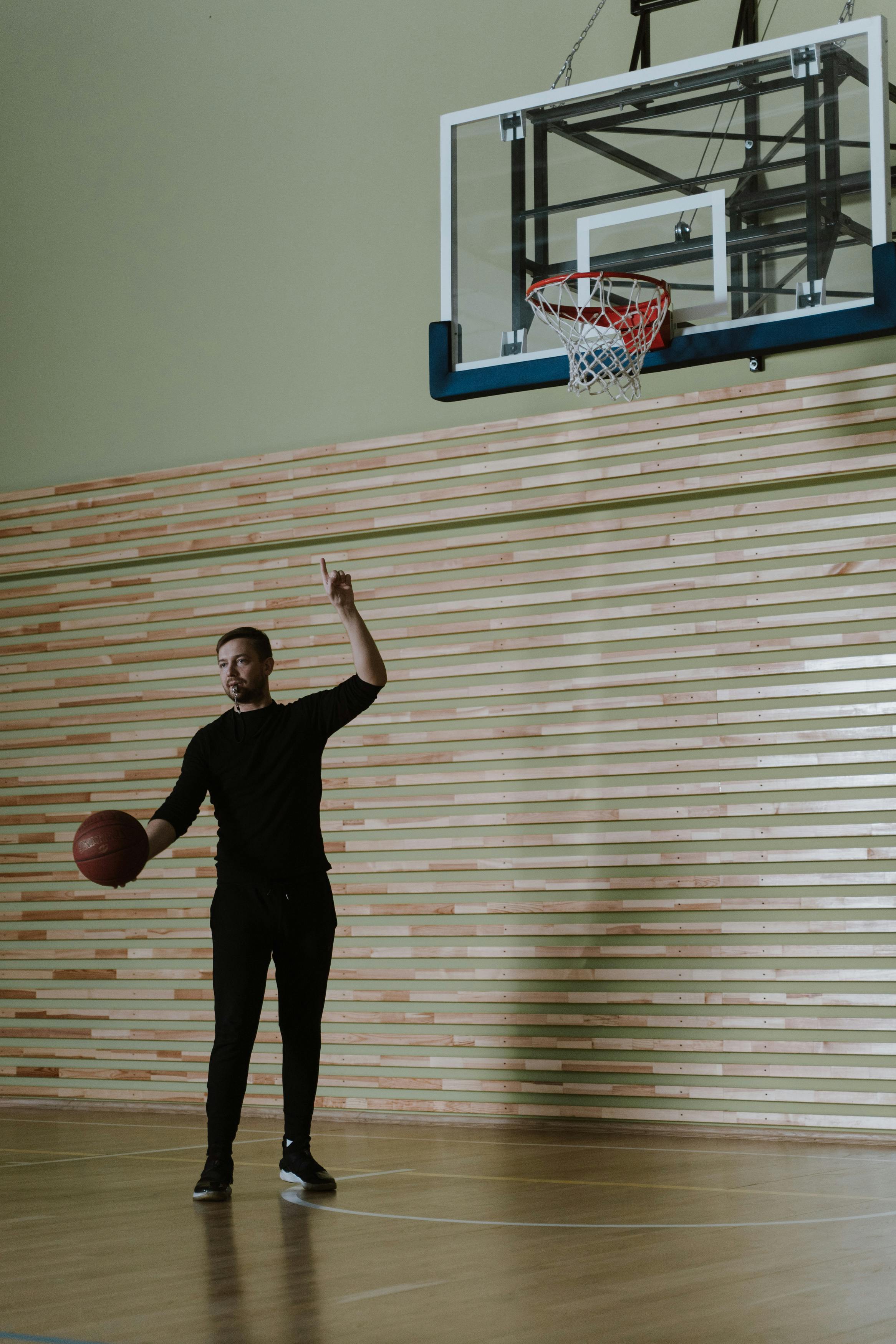 a man pointing to a basketball ring