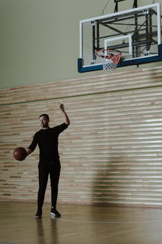 Basketball coach giving instructions on an indoor court with a basketball in hand.