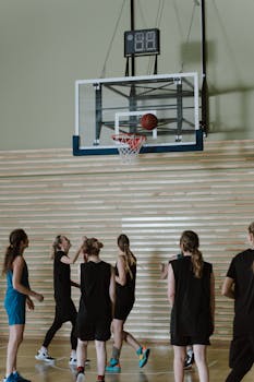 A team of young women playing basketball indoors, aiming for the hoop.