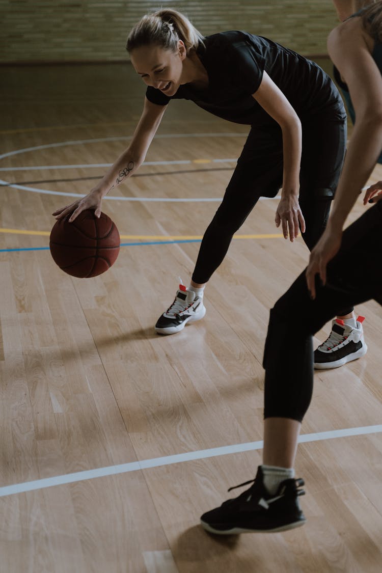 Women Dribbling A Basketball On The Wooden Court