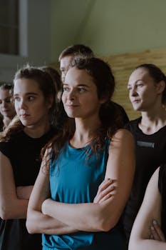 Group of confident women posing indoors with crossed arms, wearing sporty attire.
