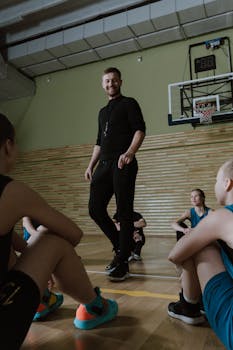Basketball coach guides young players in an indoor training session, focusing on teamwork and strategy.