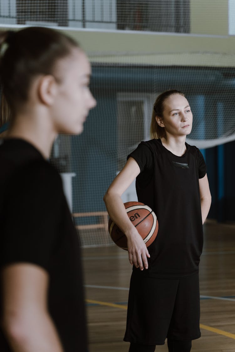 A Woman In Black Sportswear Holding A Basketball Ball