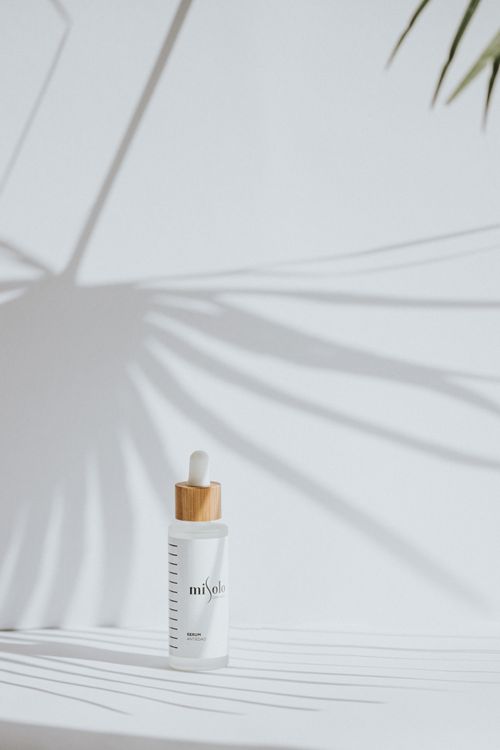 Free Minimalist skincare dropper bottle casting elegant shadows on white surface. Stock Photo