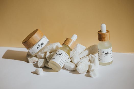 Natural skincare products displayed with bamboo lids and rocks on white surface for a clean aesthetic.