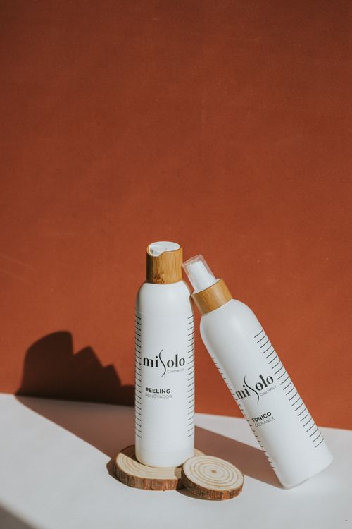 Free Two white skincare bottles on a warm red backdrop with wooden details. Stock Photo