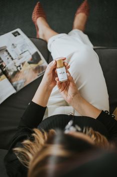 Overhead shot of a woman holding skincare serum indoors, featuring lifestyle and relaxation.