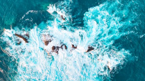 Free Dynamic aerial photo of waves crashing on rocks off the coast of Portugal, showcasing vibrant blue ocean waters. Stock Photo