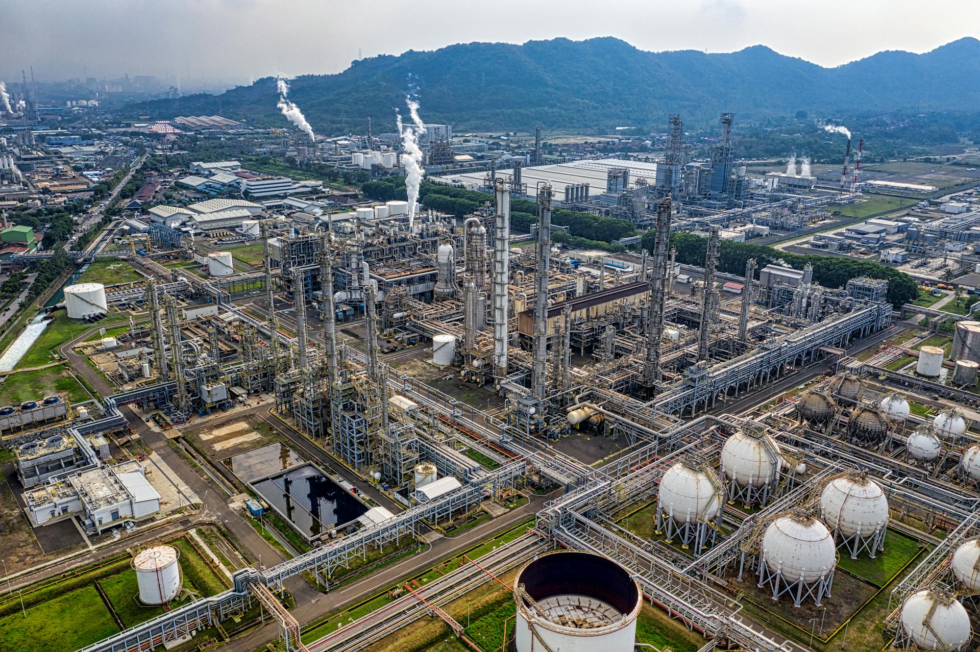 Aerial view of a large industrial oil refinery in Banten, Indonesia with storage tanks and pipelines.