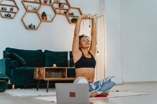 Free A woman in sportswear practicing yoga at home with a laptop nearby. Stock Photo