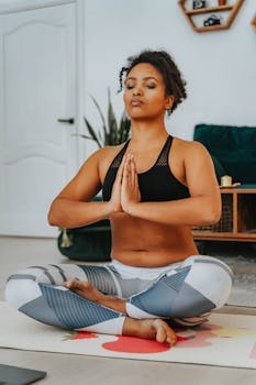 A woman meditating in lotus position on a yoga mat, embracing healthy living indoors.