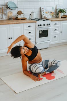 A woman practices yoga in a light-filled kitchen, showcasing a blend of fitness and home comfort.