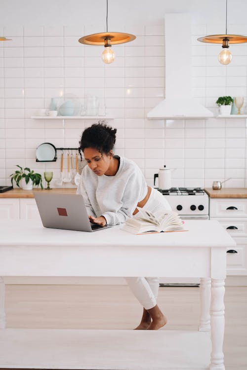 Woman in White Sweater Using a Laptop at Home