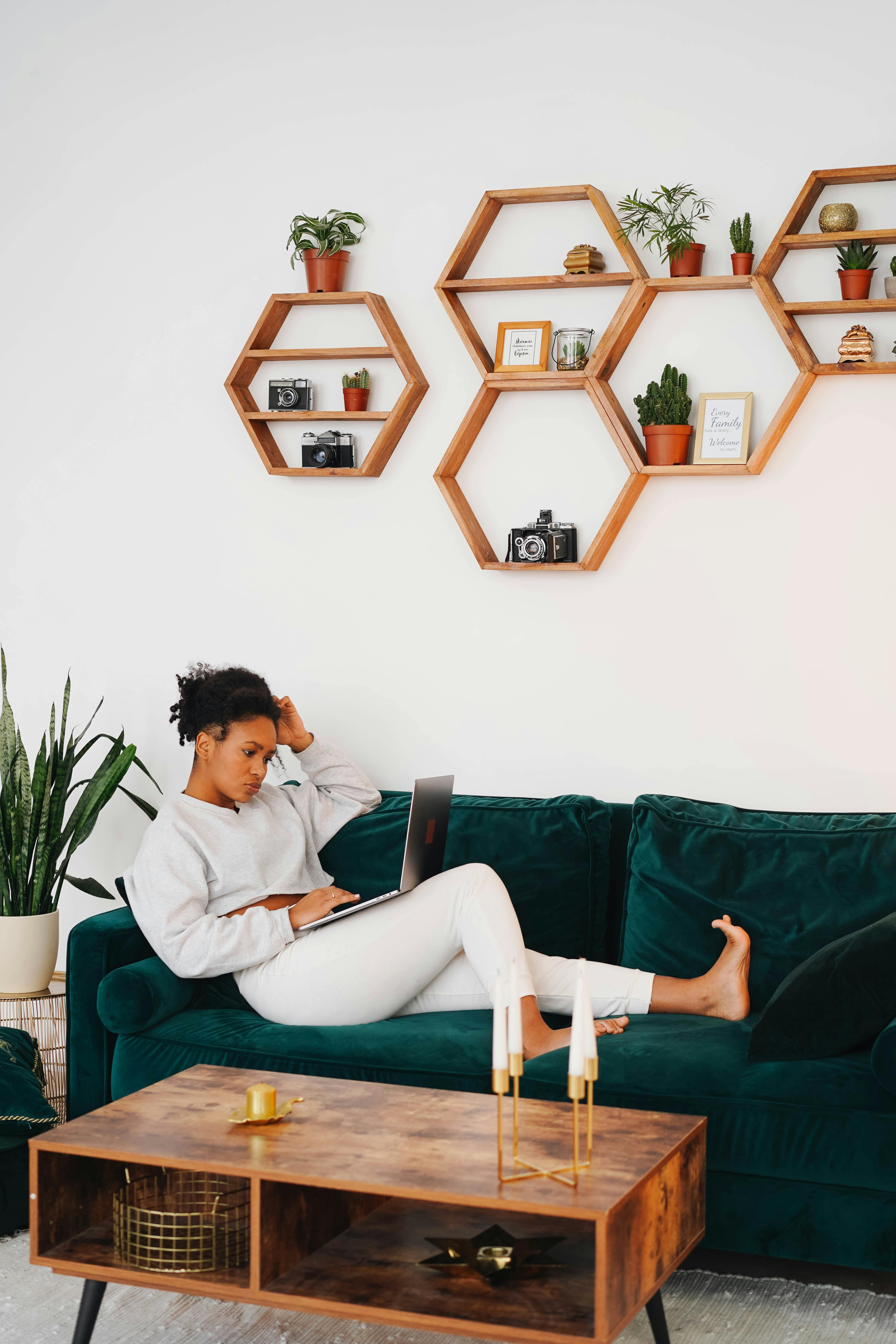 woman in white sweater using a laptop while sitting on the sofa