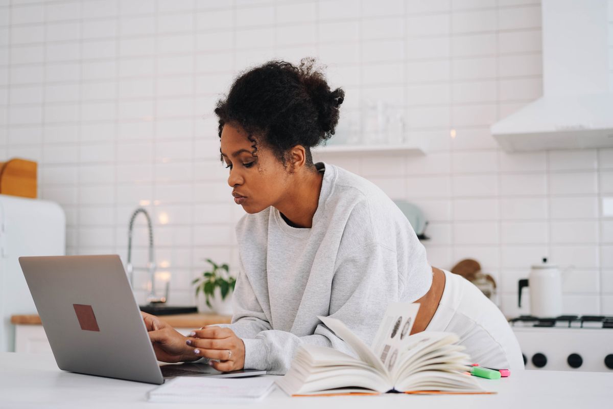 Apprenante suivant un cours en ligne sur une LXP, ordinateur portable et support ouvert
